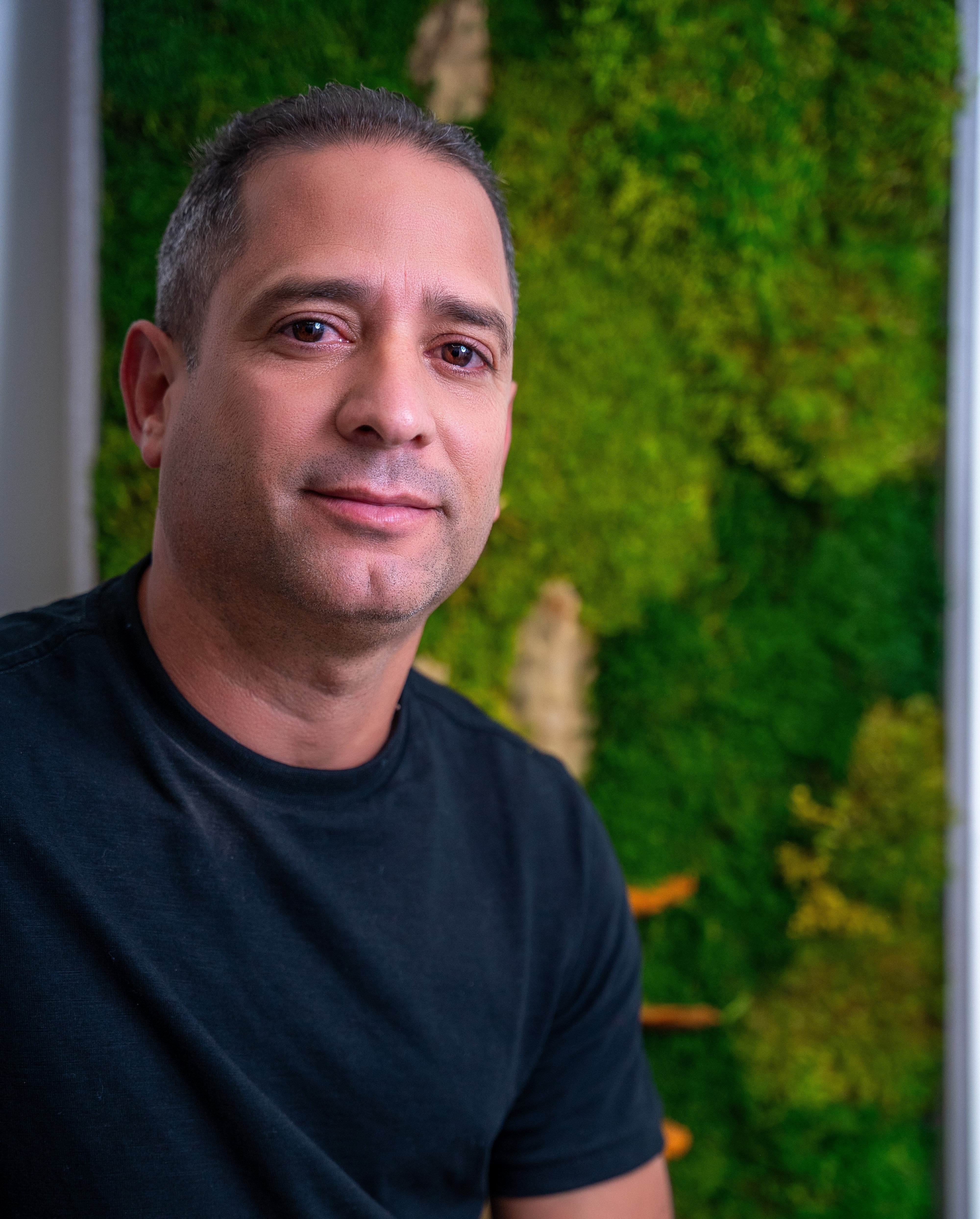 Portrait of the founder of MBD Biophilic Design standing in front of a preserved moss wall installation.
